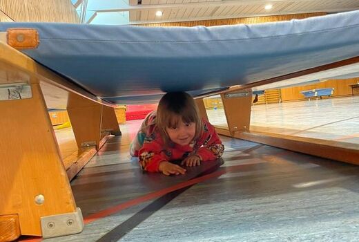 Ein Junge robbt durch einen engen Gang aus Turnmatten.