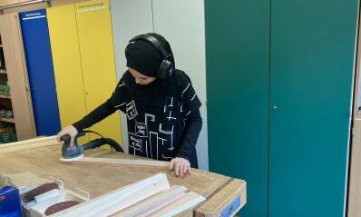 Eine junge Frau schleift ein Stück Holz