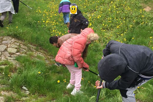 Schüler und Schülerinnen beim Müll sammeln im gründen Graben
