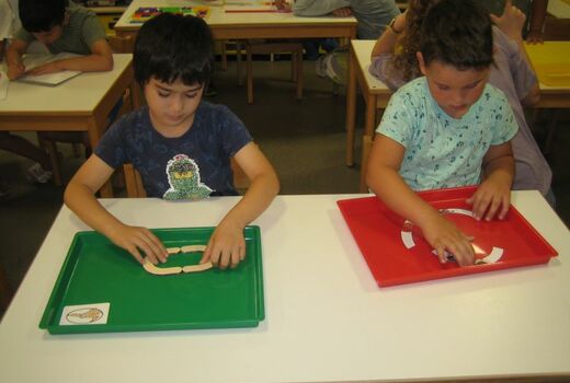 Zwei Kinder legen ein O aus einzelnen Bestandteilen zusammen.