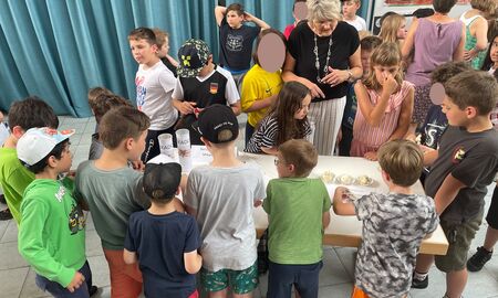 Schülerinnen und Schüler laufen in einem Rundgang herum und schauen sich an verschiedenen Tischen die erstellten und präsentierten Dinge an.