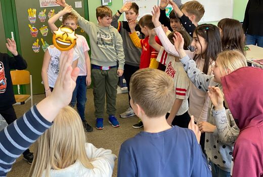 zwei Klassen schwingen die Arme und singen