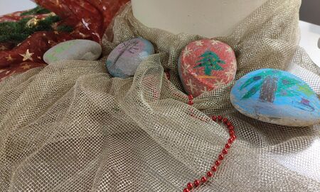 Es sind vier bemalte Steine zu sehen. Es wurden geschmückte Tannenbäume auf die Steine gemalt.