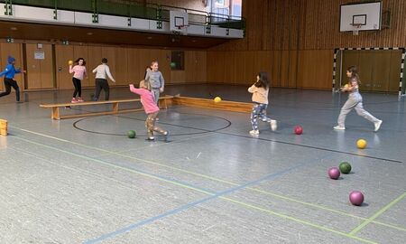 Kinder spielen in der Turnhalle mit Bällen