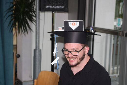 Ein Schüler, der verabschiedet wird, hat seinen Hut auf und lächelt dabei.