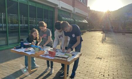 Ein Team aus zwei Mädchen und zwei Jungen puzzeln an einem Tisch