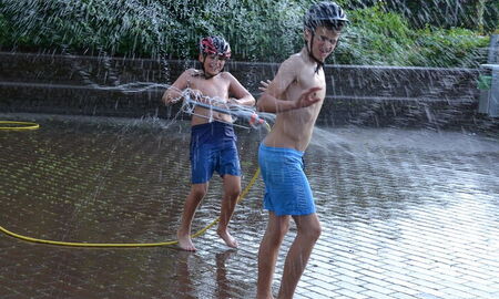 Zwei Jungen erfrischen sich am Rasensprenger