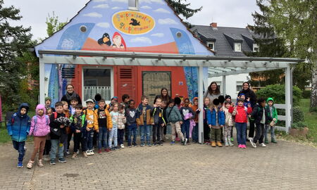 Zu sehen sind Kinder der Klasse eins vor dem Haus des Puppentheater Plappermauls