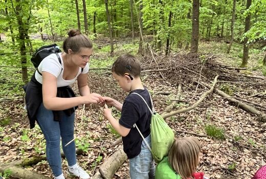 Junge Frau hilft einem Jungen beim Knoten im Wald