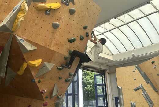 Ein Junge klettert eine schräge Wand hoch.