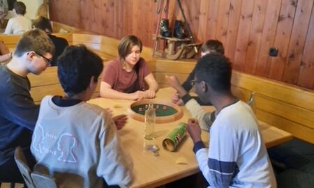 Fünf Schüler sitzen an einem Tisch und spielen ein Würfelspiel