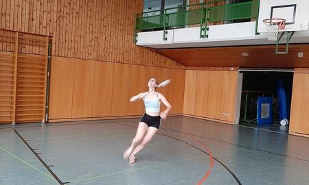 Eine Spielerin schaut in die Luft und schaut nach dem Ball. Sie hät einen Badminton Schläger in der Hand.