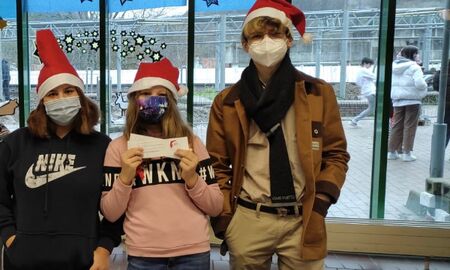 Auf dem Bild sieht man drei Schülerinnen und Schüler am Nikolausverkaufsstand in der Aula. Verkaufsstand für die Nikoläuse mit Verkaufsteam in der Aula