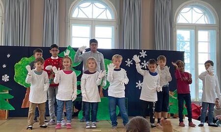 Kinder haben weiße Hemden und weiße Handschuhe an und Gebärden zu Musik