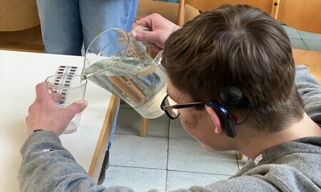 Ein Junge füllt vorsichtig ein Wasserglas