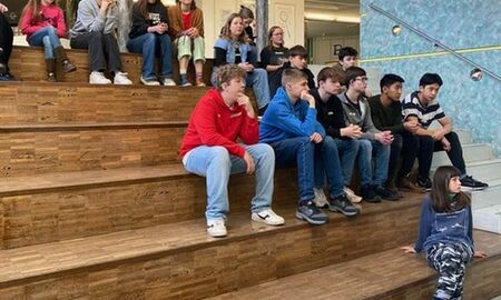 Jugendliche sitzen in einer Aula