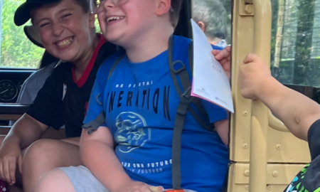 Zwei Schüler sitzen in einem offenen Jeep im Heidelberger Zoo und lachen.