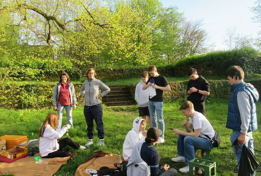 SchülerInnen und Erzieherinnen stehen bzw. sitzen auf der Wiese