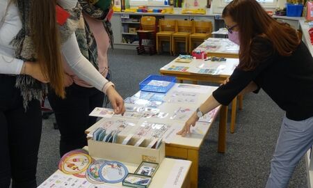 Drei Frauen stehen um Tische, die mit Fördermaterialien bedeckt sind