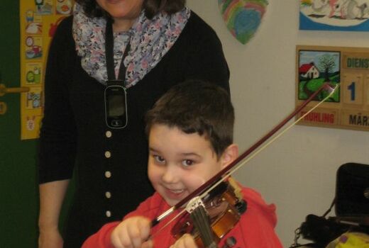 Ein Junge lacht beim Geige spielen.