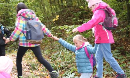 Zwei Mädchen balancieren auf dem Baumstamm ein Mädchen gibt Hilfestellung