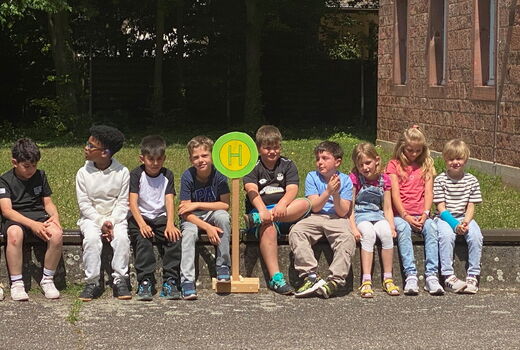 Kinder warten an einem Haltestellenschild