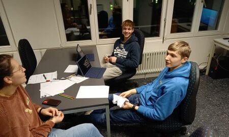 kreativer Austausch zwischen zwei Jugendlichen und einer Lehrerin