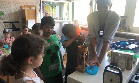 Die BeKi-Referentin quetscht mit den Kindern gemeinsam Hafer, sodass Haferflocken entstehen.