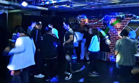 Einige SchülerInnen stehen auf der Tanzfläche und tanzen. Die Lichtanlage leuchtet.