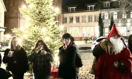 Der Nikolaus beschenkt SchülerInnen auf dem Marktplatz in Neckargemünd. Im Hintergrund steht ein Tannenbaum.