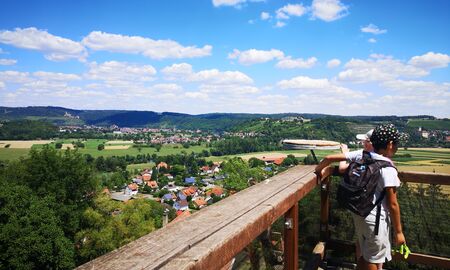 Ein Schüler und eine Schülerin genießen die Aussicht und schauen über ein Holzgeländer ins Tal hinunter
