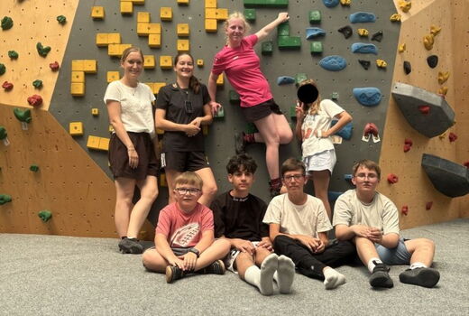 Sechs SchülerInnen und zwei LehrerInnen posieren vor einer Boulderwand.