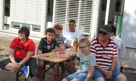 Schüler und ein Erzieher sitzen auf einer Bank.