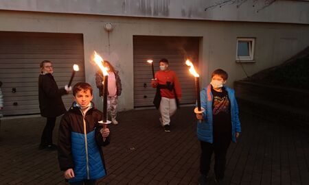 Zu sehen sind fünf SchülerInnen mit Fackeln. Sie stehen auf dem Schulgelände.