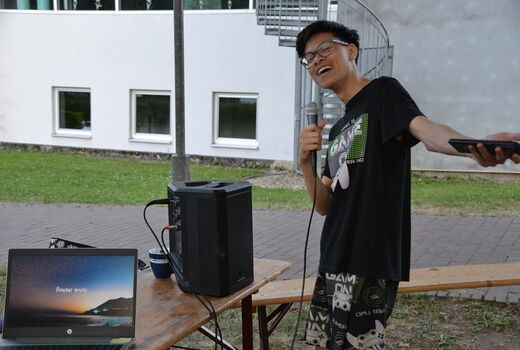 Ein Junge steht vor der Karaoke-Anlage und hat ein Mikrofon in der Hand.