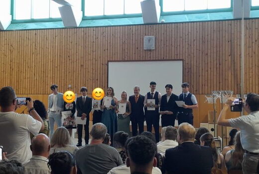 Blick Richtung Bühne: Die Absolventen der 10a lächeln und präsentieren stolz ihre Abschlusszeugnisse.