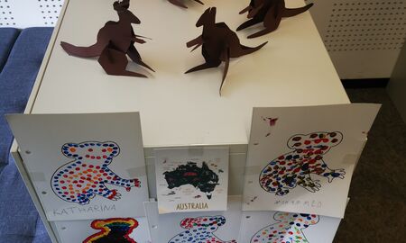 An einem Regal hängen elf bunte Punktebilder von Koalas. Oben in der Mitte hängt eine Kinderkarte von Australien. Oben auf dem Regal stehen viele gebastelte Kängurus.