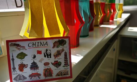 Auf einer Fensterbank steht vorne eine bildliche Informationskarte zu China. Dahinter stehen viele bunte gebastelte Laternen in einer Reihe auf der Fensterbank.