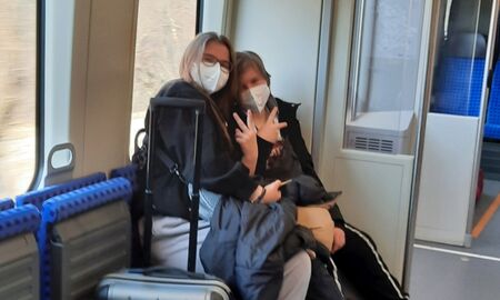 Zwei Schülerinnen mit Gepäck im Zug zeigen das Victory-Zeichen