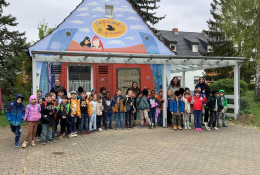 Zu sehen sind Kinder der Klasse eins vor dem Haus des Puppentheater Plappermauls