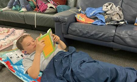 Ein junge liegt auf seinem Matratzenlager und liest ein Buch