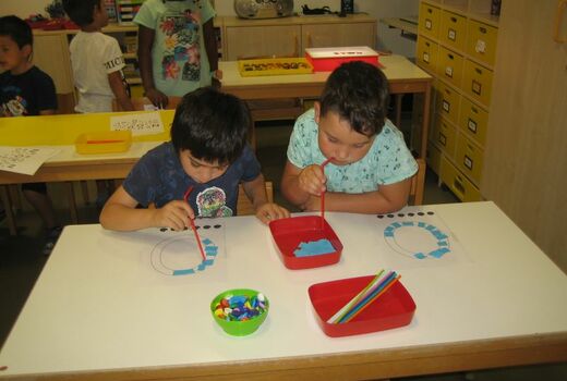 Zwei Jungen saugen mit einem Strohhalm Papierschipsel an.