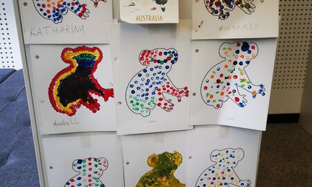 An einem Regal hängen elf bunte Punktebilder von Koalas. Oben in der Mitte hängt ein Schild mit einer Kinderkarte von Australien.