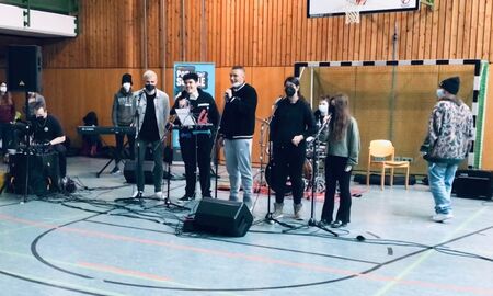Eine Gruppe von Schülern steht in der Turnhalle und macht Musik