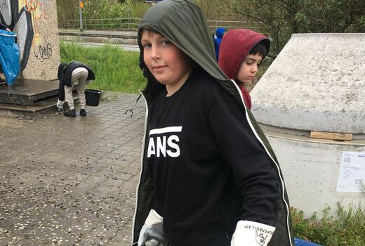 Ein Schüler mit einem Eimer und Arbeitshandschuhen