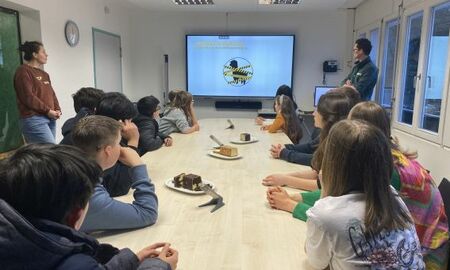 Eine Gruppe Jugendlicher sitzt an einem Tisch und schaut auf ein interaktives Panel