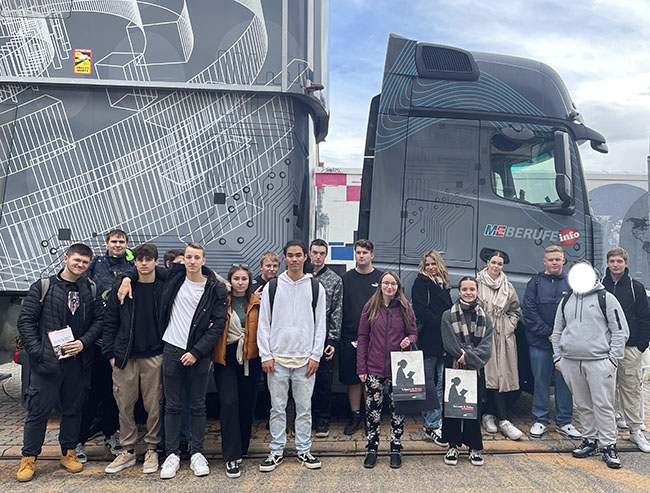 Eine Gruppe von Schülerinnen und Schülern der Beruflichen Bildung positionieren sich für ein Gruppenbild vor einem LKW der Messe.