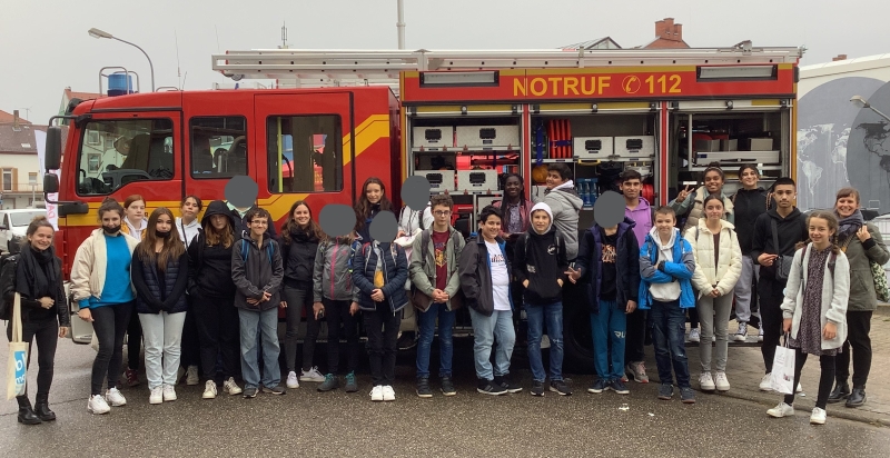 Vierundzwanzig SchülerInnen und drei Lehrerinnen stehen vor einem Feuerwehrwagen und lachen in die Kamera.